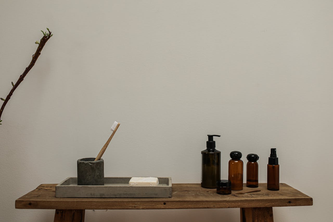 A rustic bathroom setup with soap and amber bottles on a wooden bench for a minimalist look.